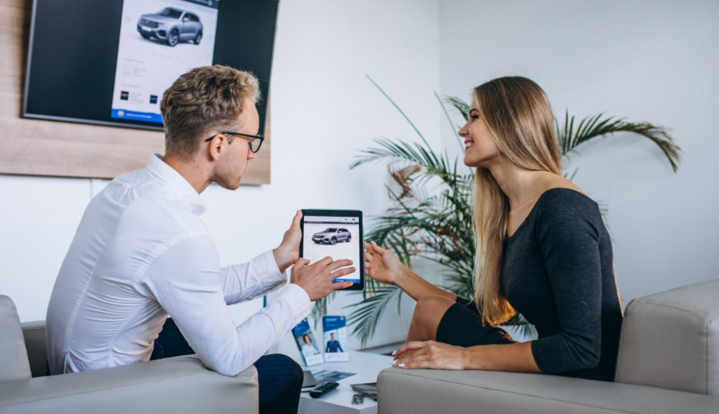 Car dealership representative showing a vehicle listing to a shopper