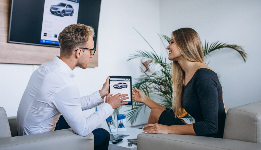 Car dealership representative showing a vehicle listing to a shopper