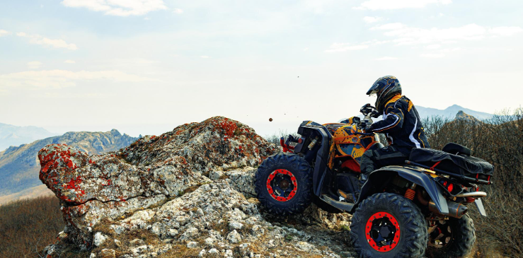 Rider in a helmet operating an ATV on a rocky mountain trail
