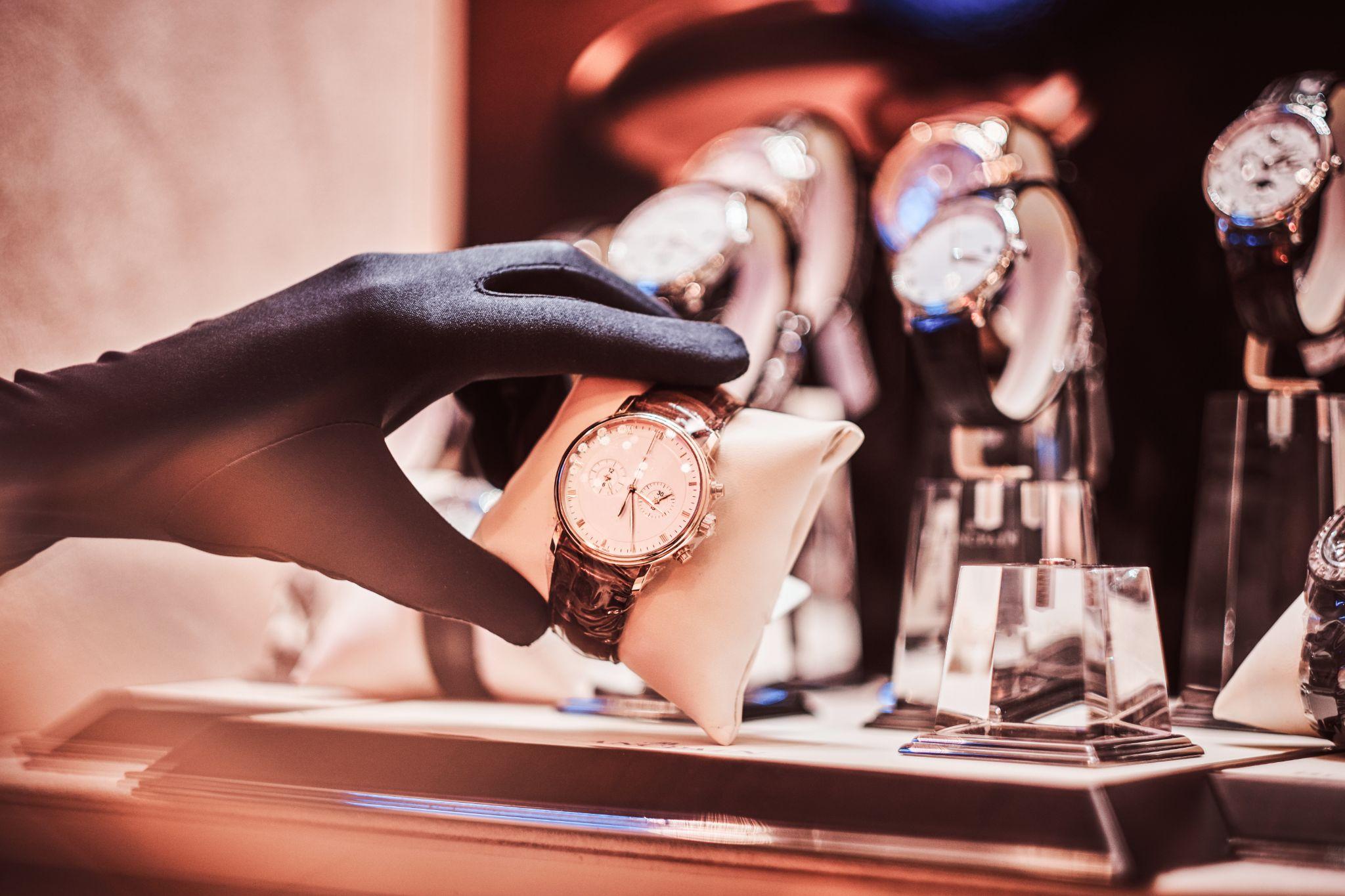 Gloved hands inspecting a second-hand luxury watch in a watch shop