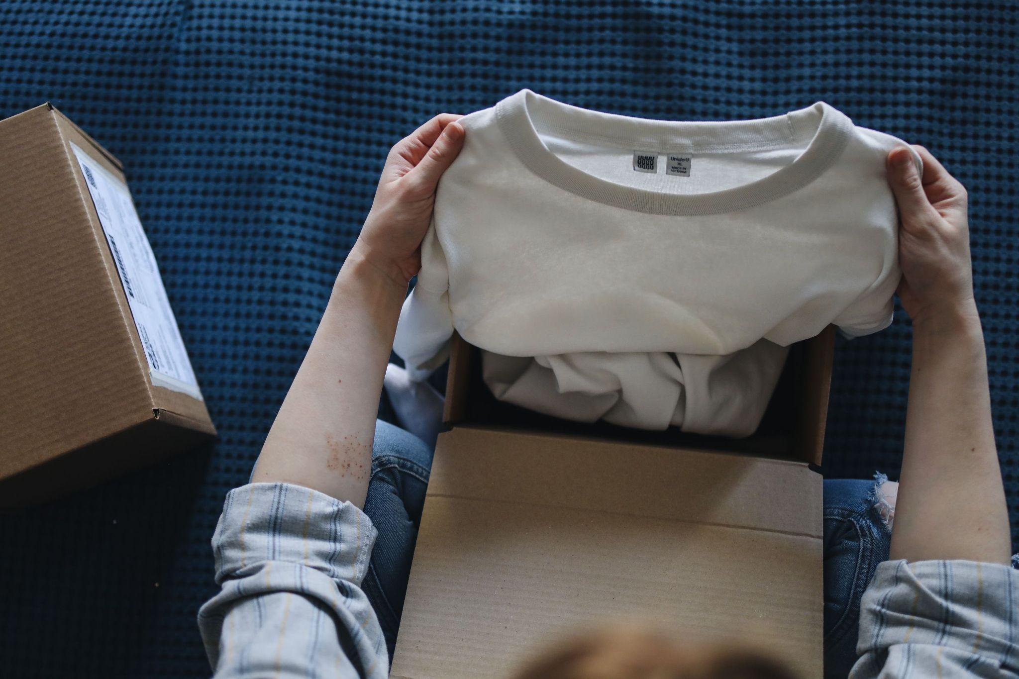 Fashion entrepreneur holding a clothing sample above a shipping box